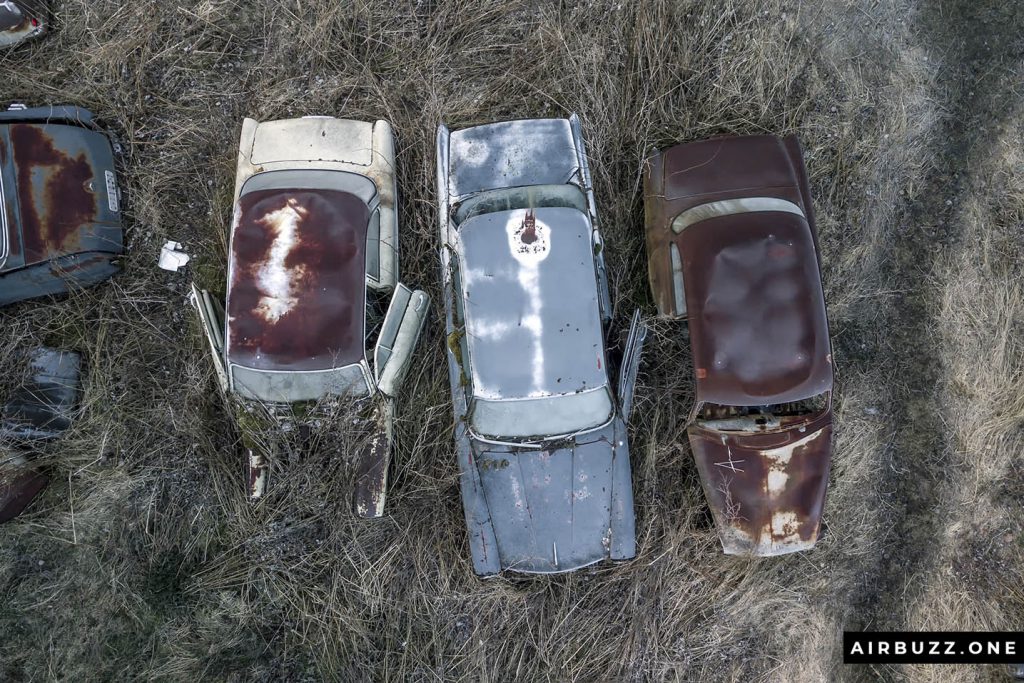 Three cars in a row waiting to rust away.